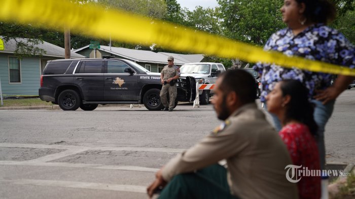 Orang-orang duduk di tepi jalan di luar Robb Elementary School saat polisi negara bagian menjaga area di Uvalde, Texas, pada 24 Mei 2022. - Seorang pria bersenjata berusia 18 tahun membunuh 14 anak dan seorang guru di sebuah sekolah dasar di Texas pada hari Selasa, menurut gubernur negara bagian itu, dalam penembakan sekolah paling mematikan di negara itu selama bertahun-tahun. (Photo by allison dinner / AFP)
