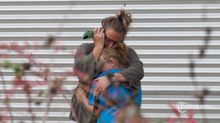Seorang wanita menangis dan memeluk seorang gadis muda saat berbicara di telepon di luar Willie de Leon Civic Center di mana konseling kesedihan akan ditawarkan di Uvalde, Texas, pada 24 Mei 2022. - Seorang pria bersenjata remaja membunuh 18 anak kecil dalam penembakan di sebuah sekolah dasar sekolah di Texas pada hari Selasa, dalam penembakan sekolah paling mematikan di AS dalam beberapa tahun. (Photo by allison dinner / AFP)